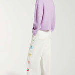 Back view of white straight leg jean on model wearing purple sweater and white sneakers, against a white background.