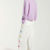 Back view of white straight leg jean on model wearing purple sweater and white sneakers, against a white background.