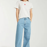 Front view of white embroidered balloon t-shirt on model wearing jeans and sneakers, against a white background.