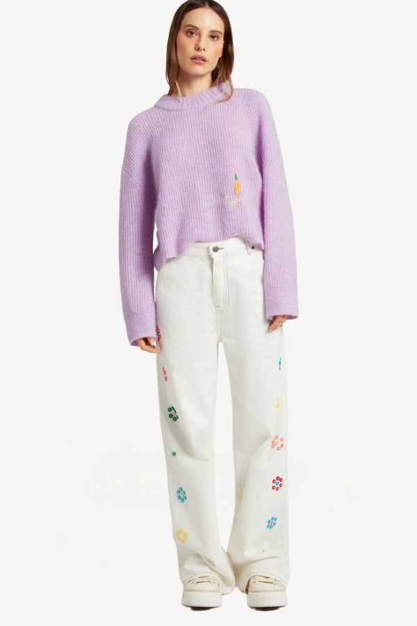 Front view of lilac embroidered sweater on model wearing white denim and sneakers, against a white background.