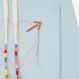 Front closeup view of pale blue embroidered heart hoodie on white background, with no model shown.