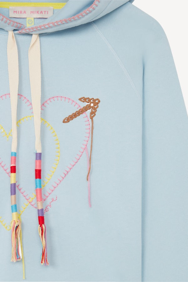 Front closeup view of pale blue embroidered heart hoodie on white background, with no model shown.