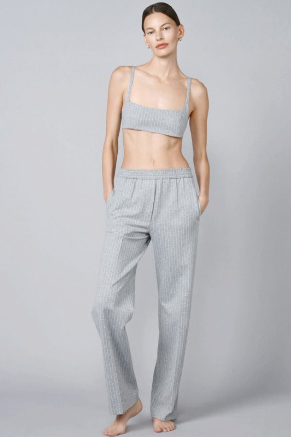 Front view of grey stripes jersey jogger pant on model wearing grey bra, against a grey background.