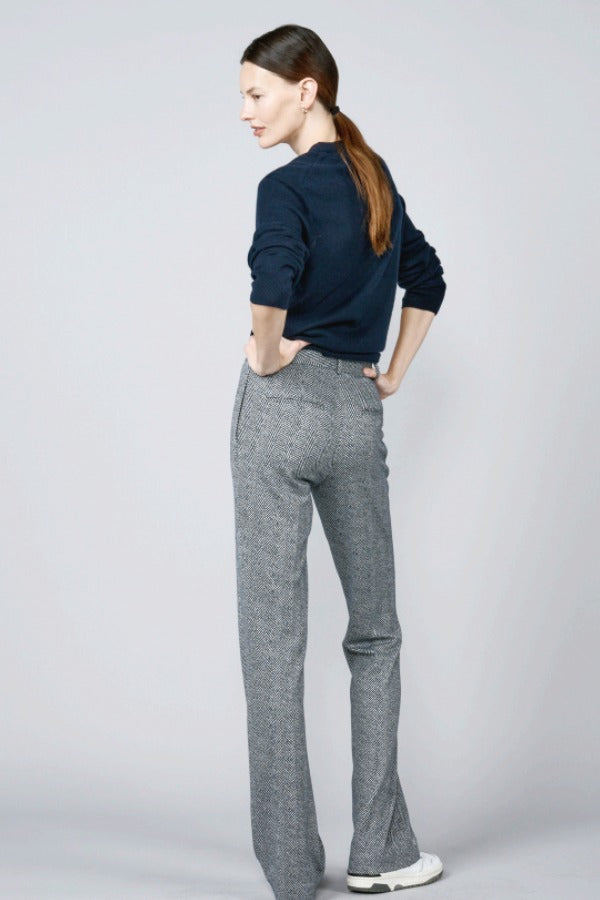 Back view of navy blue herringbone paris pant on model wearing navy top and sneakers, against a white background.