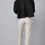 Back view of beige striped universal pant on model wearing black jacket and loafers, against a grey background.