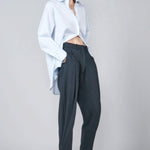 Front view of navy pinstriped jersey sarouel pant on model wearing blue shirt and heels, against a grey background.