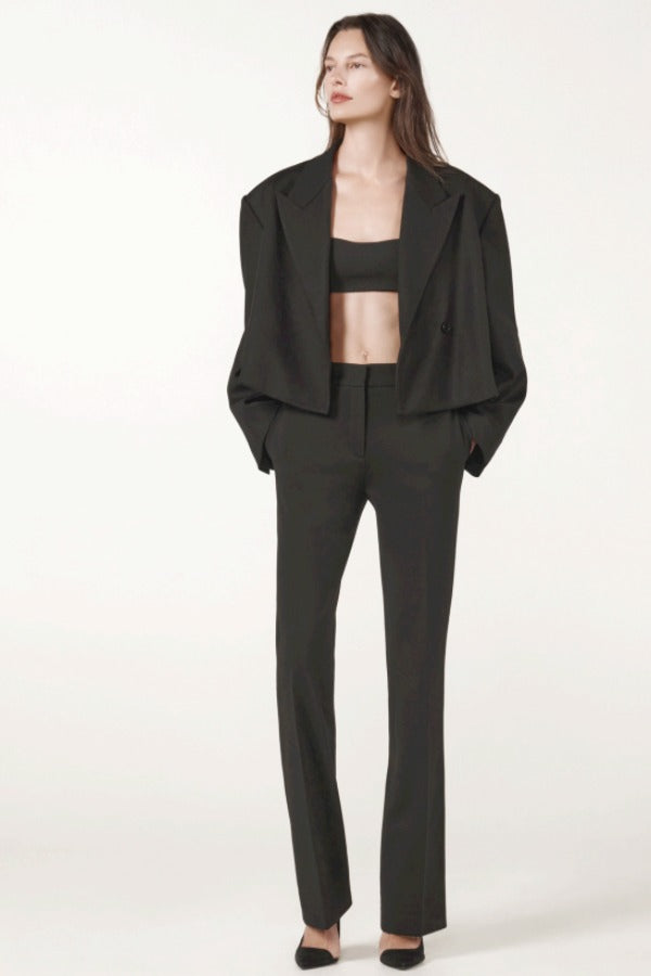Front view of black the jacket on model wearing black pants and heels, against a white background.
