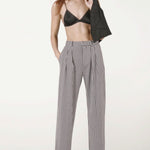 Front view of black and white houndstooth jersey long legged pant on model wearing black bra and heels, against a white background.