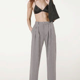 Front view of black and white houndstooth jersey long legged pant on model wearing black bra and heels, against a white background.