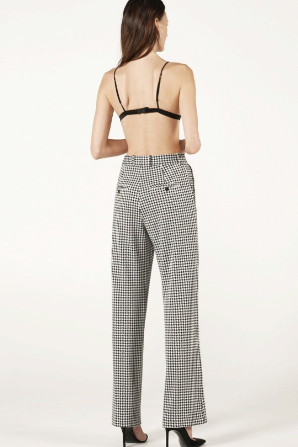 Back view of black and white houndstooth jersey long legged pant on model wearing black bra and heels, against a white background.