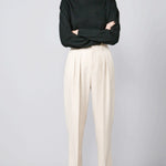 Front view of creme long legged pant on model wearing black sweater and loafers, against a grey background.