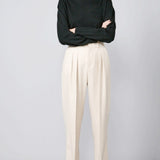 Front view of creme long legged pant on model wearing black sweater and loafers, against a grey background.