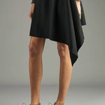 Side view of pair of sand antoine desert boots on model wearing black dress, against a white background,