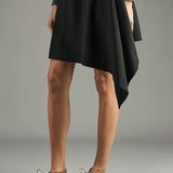 Side view of pair of sand antoine desert boots on model wearing black dress, against a white background,