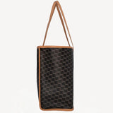 Side view of black/tan canvas cube and calf cab tote on white background, with no model shown.