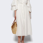 Front view of white fiesta shirt dress on model wearing beige heels, against a white background.