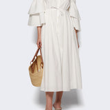 Front view of white fiesta shirt dress on model wearing beige heels, against a white background.