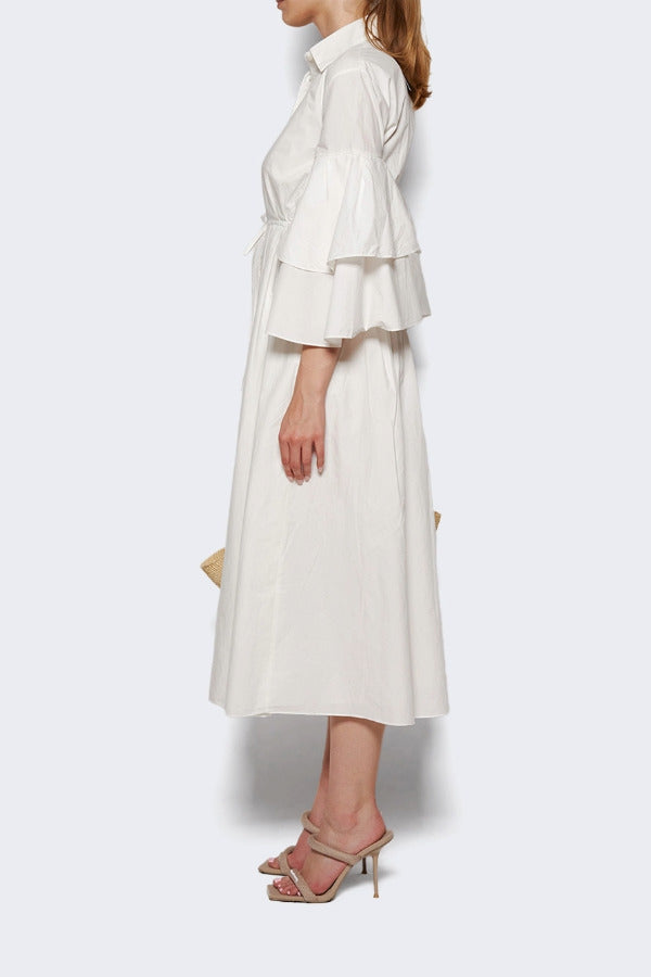 Side view of white fiesta shirt dress on model wearing beige heels, against a white background.
