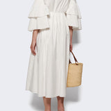 Back view of white fiesta shirt dress on model wearing beige heels, against a white background.