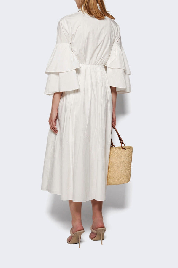 Back view of white fiesta shirt dress on model wearing beige heels, against a white background.