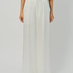 Woman wearing a beige top and wide-leg pants on a white background