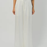 Woman wearing a beige top and wide-leg pants on a white background