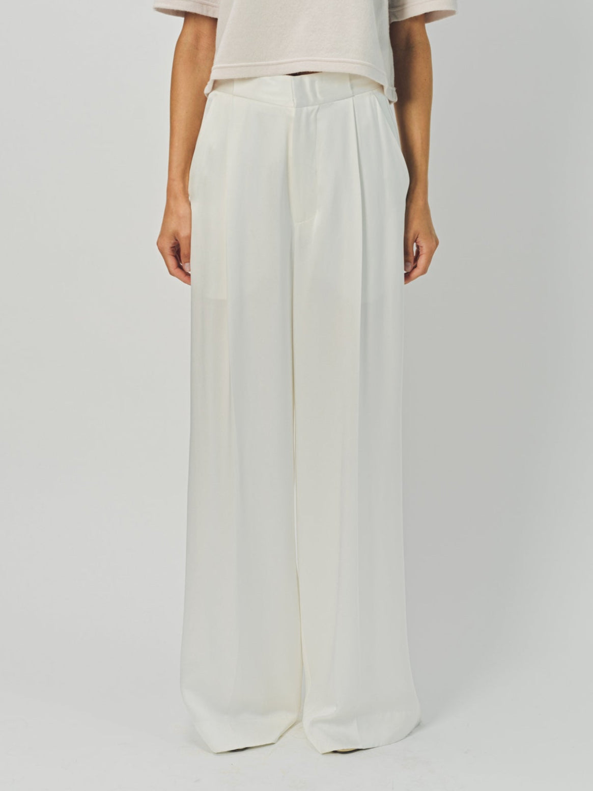 Woman wearing a beige top and wide-leg pants on a white background