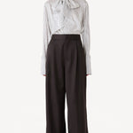 Front view of brown bogart wool trousers on model wearing striped blouse, against a white background.