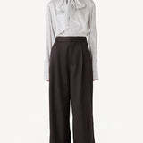 Front view of brown bogart wool trousers on model wearing striped blouse, against a white background.