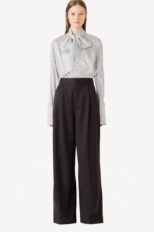 Front view of brown bogart wool trousers on model wearing striped blouse, against a white background.