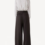 Back view of brown bogart wool trousers on model wearing a striped blouse, against a white backgorund.
