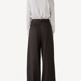 Back view of brown bogart wool trousers on model wearing a striped blouse, against a white backgorund.
