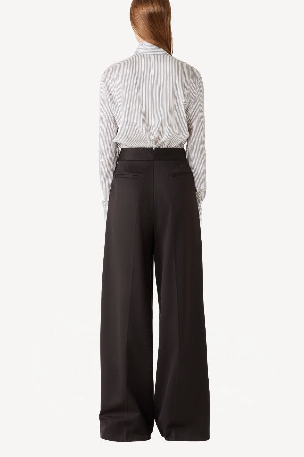 Back view of brown bogart wool trousers on model wearing a striped blouse, against a white backgorund.