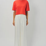 Front view of orange cashmere cropped t-shirt on model wearing white pants, against a white background.