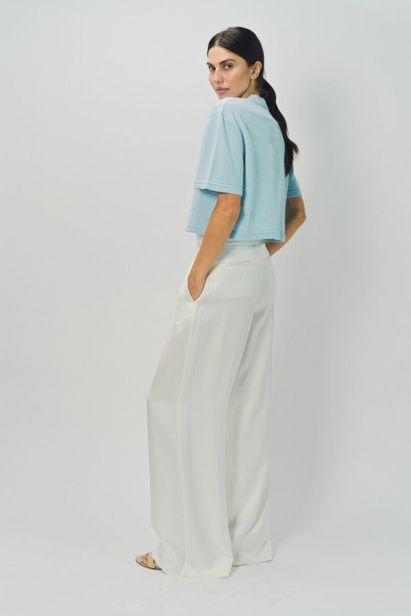 Side view of cielo cashmere cropped t-shirt on model wearing white pants, against a white background.