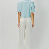 Back view of cielo cashmere cropped t-shirt on model wearing white pants, against a white background.