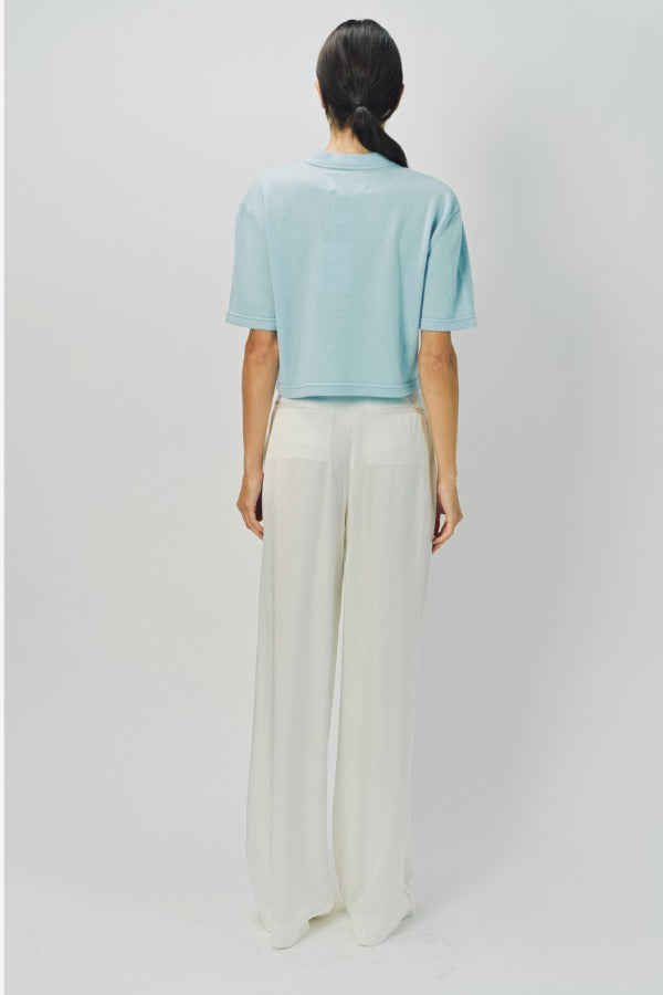 Back view of cielo cashmere cropped t-shirt on model wearing white pants, against a white background.