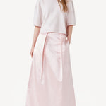 Front view of nude cashmere cropped t-shirt on model wearing pink skirt, against a white background.