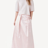 Front view of nude cashmere cropped t-shirt on model wearing pink skirt, against a white background.