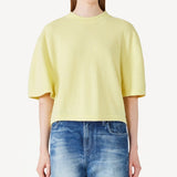 Front view of yellow cashmere cropped t-shirt on model wearing jeans, against a white background.