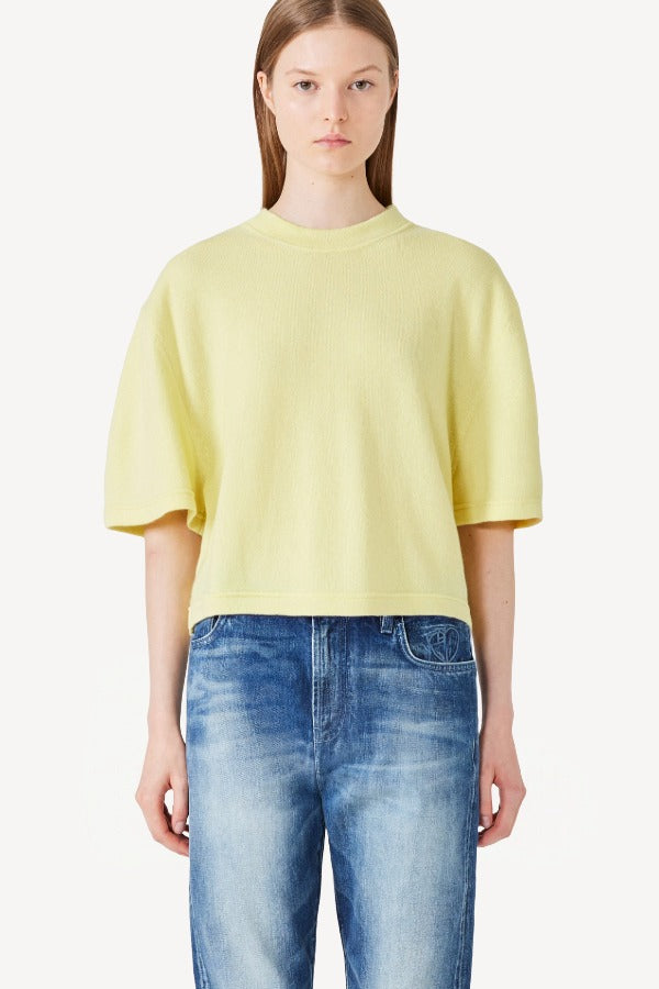 Front view of yellow cashmere cropped t-shirt on model wearing jeans, against a white background.