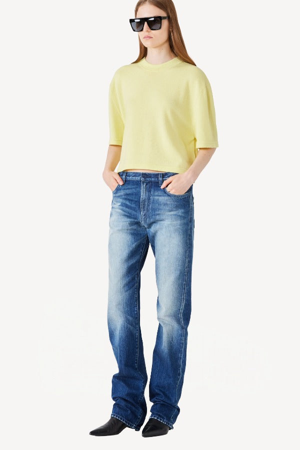 Front view of yellow cashmere cropped t-shirt on model wearing jeans and boots, against a white background.