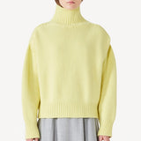 Front view of yellow cashmere high neck sweater on model wearing grey skirt