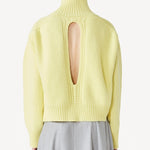 Back view of yellow cashmere high neck sweater on model wearing grey skirt, against a white background.