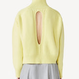 Back view of yellow cashmere high neck sweater on model wearing grey skirt, against a white background.