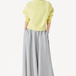 Front view of yellow cashmere high neck sweater on model wearing grey skirt, against a white background.
