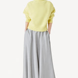 Front view of yellow cashmere high neck sweater on model wearing grey skirt, against a white background.