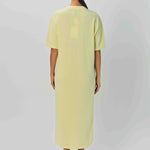 Back view of yellow cashmere long t-shirt dress on model wearing sandals, against a white background.
