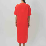 Back view of orange cashmere long t-shirt dress on model wearing sandals, against a white background.