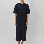 Front view of navy cashmere long t-shirt dress on model wearing sandals, against a  white background.